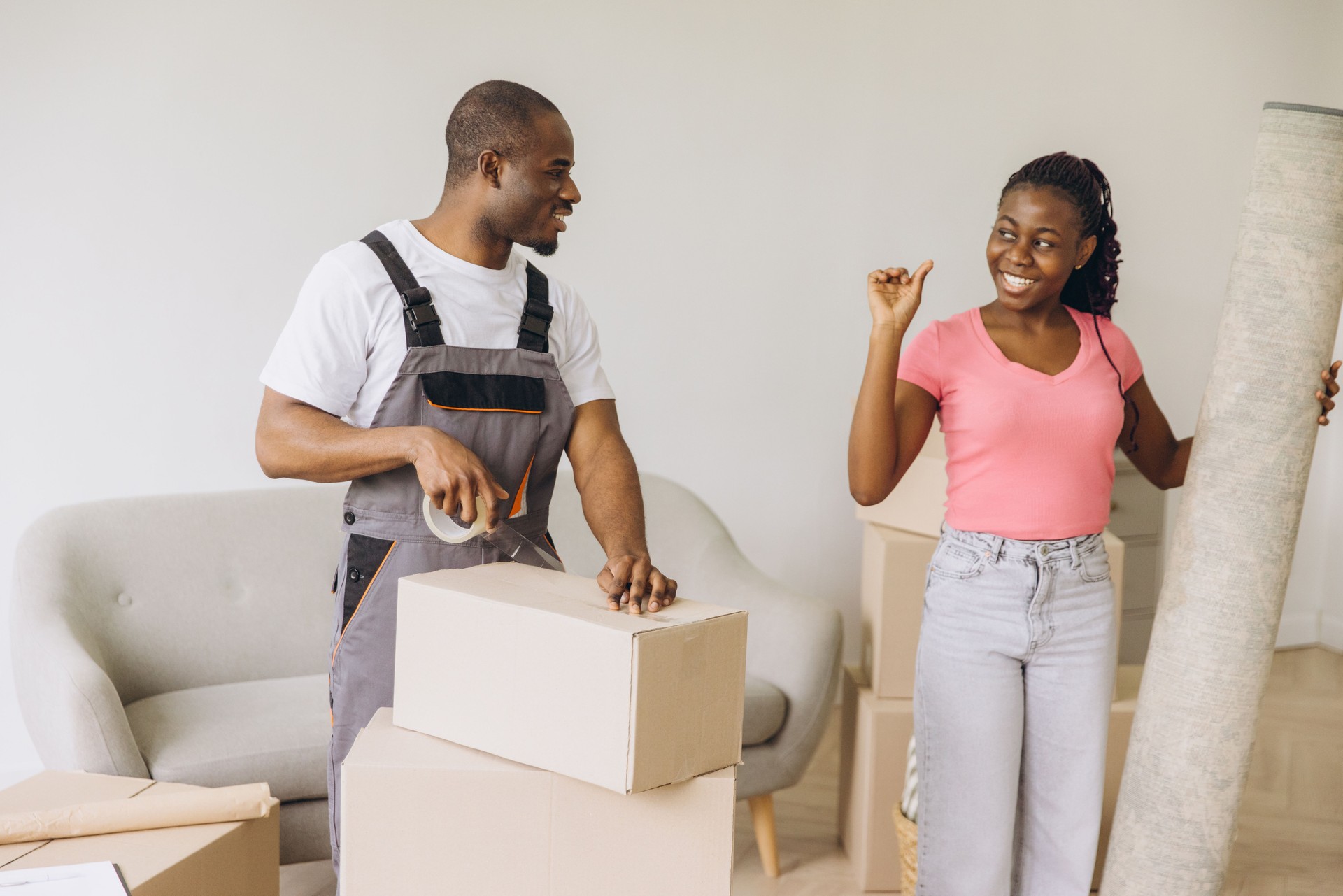 Afroamerikanische Umzugsunternehmen packen Kisten und Teppich in neuer Wohnung
